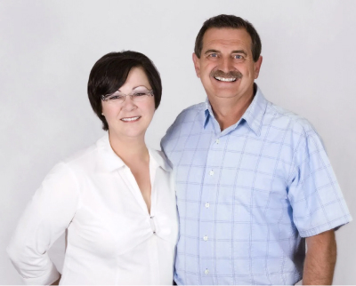 man and women smiling in front of a white wall