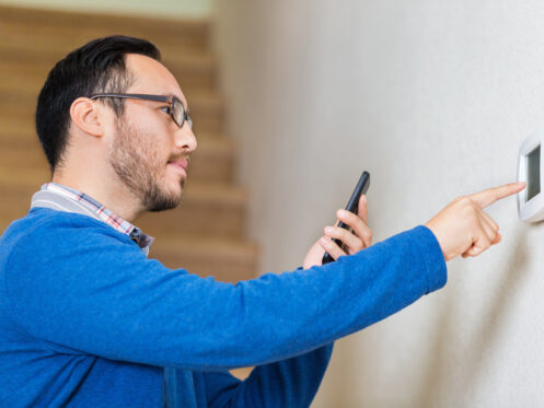 A man checking his thermostat with his phone.